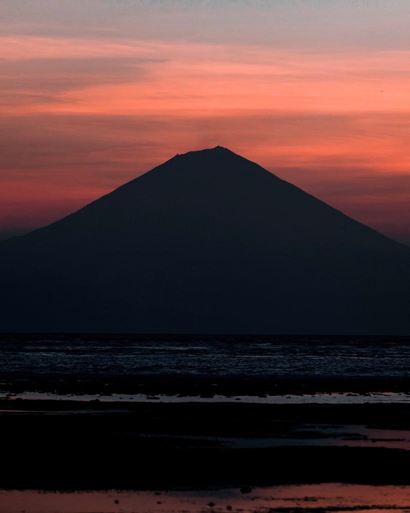 Captivating silhouette of Mount Rinjani against a vibrant sunset sky in West Nusa Tenggara, Indonesia.