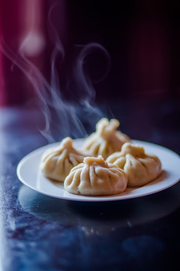 Delicious and steaming hot dumplings served on a ceramic plate.