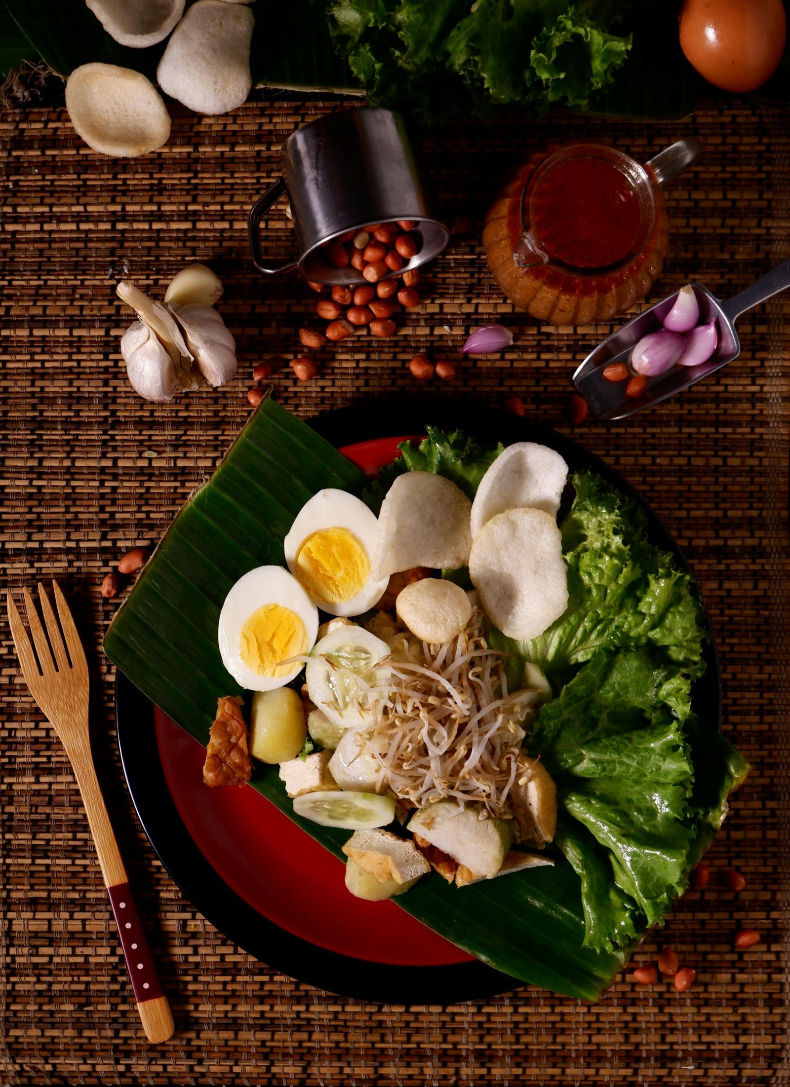 Flat lay of traditional Indonesian Gado-Gado salad with peanut sauce and fresh ingredients.