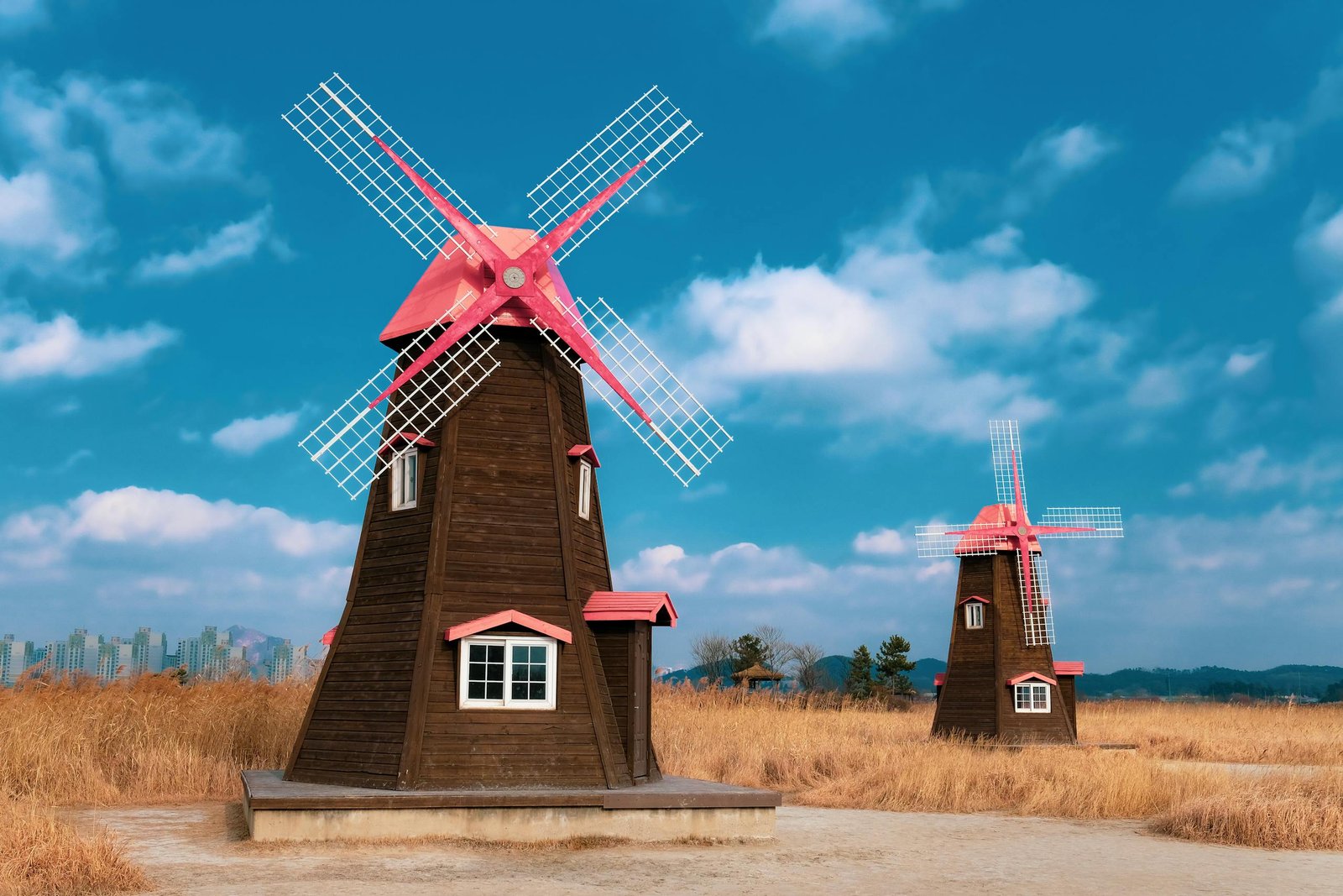 Scenic view of traditional windmills in the countryside of Incheon, South Korea, under a bright blue sky.
