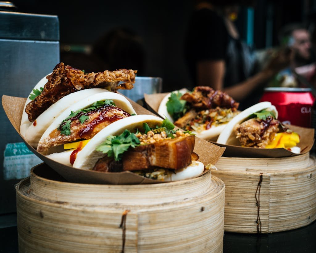 Tasty bao buns with meat and vegetables, captured in a vibrant street market in England.