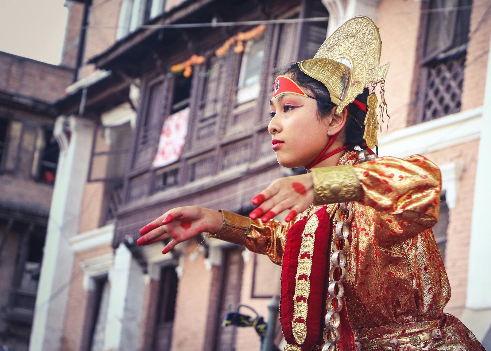 Young girl in vibrant traditional wear dancing at a Nepali festival.